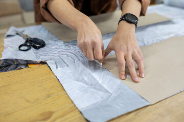 A fashion designer or tailor uses chalk to trace a sewing pattern onto fabric. A close-up concept of the dressmaking process, craftsmanship, and bespoke clothing design.