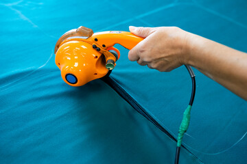 A cutter or pattern cutter uses an electric rotary cutter to cut through a stack of fabric in a garment factory. A concept of the textile industry and mass production.