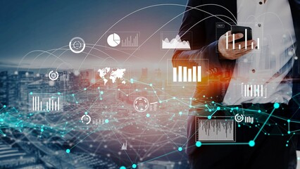 A businessperson stands against a city skyline, using a smartphone as digital analytics and graphs overlay the image, illustrating modern technology in finance. Xenic