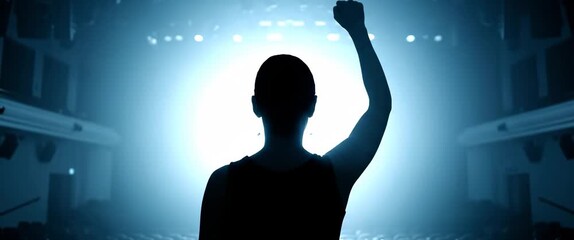 Silhouette of performer on stage spotlight raising arm in victory celebration