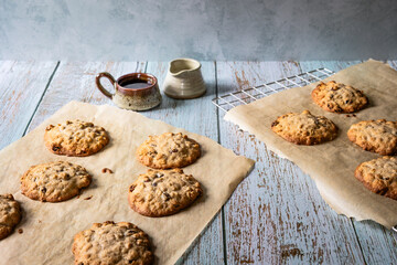 Home baked oat and raisin cookies on a wooden table with a cup of coffee