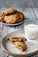 Home baked oat and raisin cookies on a wooden table with a glass of milk