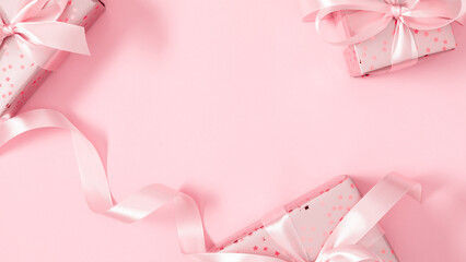 Flat lay of pink gift boxes with satin ribbons on pastel background. Elegant minimal Christmas or birthday composition, festive frame with copy space for greeting card or banner.