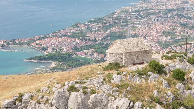 Ancient stone chapel on a coastal mountain ridge with panoramic sea view of the Dalmatian coast.