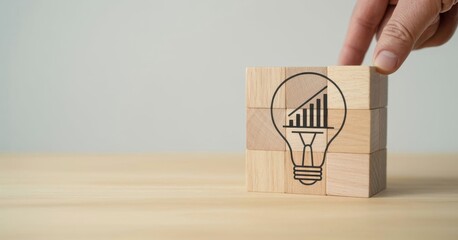 Innovative Insight: A hand meticulously places a wooden block, completing a stacked structure, symbolizing innovation. The block features a drawn lightbulb and a rising graph.