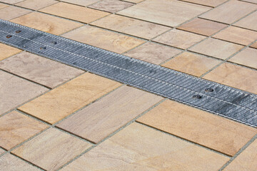 Fototapeta premium METAL RAINWATER COLLECTION GRID IN A PEDESTRIAN ZONE with concrete flooring made with blocks of rectangular shape