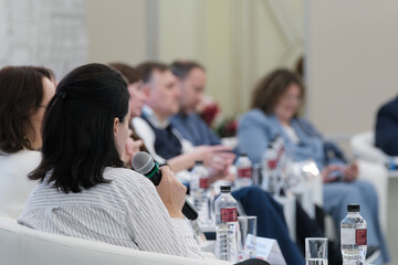 Professional gathering featuring individuals in a discussion setting with a focus on speaker and audience