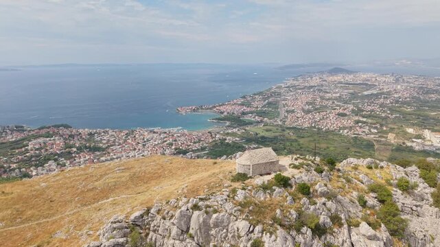 Ancient stone chapel on a coastal mountain ridge with panoramic sea view of the Dalmatian coast.