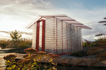 Old school greenhouse made out of metal construction and used jars. Photo taken during sunset. 
