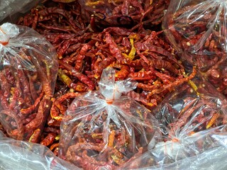 Bulk quantity of dried red chili peppers packaged and ready for sale, likely at a market or grocery store.