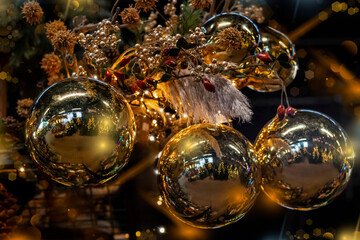 Sparkling floral Christmas background with large golden balls and festive lights, selective focus