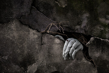 Mummy's hand wrapped in bandage rises through stone slabs of a grave or crypt. Background with copy space. Horrible risen dead mummy monster for Halloween horror concept