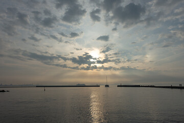 a sailboat entering the sea under a cloudy sky
