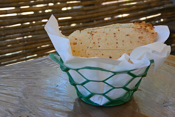 Pane carasau - traditional flatbread from Sardinia. Pane carasau in the green basket, on the table