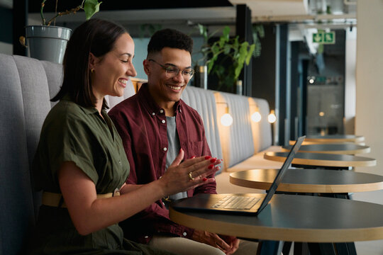 Successful business people applauding while looking at laptop screen while sitting in office