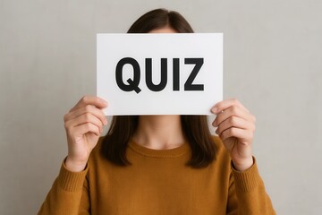 QUIZ is written on a white paper in front of a woman holding it up