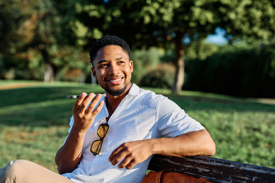 Young man enjoys sunny day while using smartphone in urban setting, highlighting his joy and connection to the world around him - Powered by Adobe