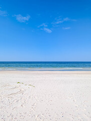 Fototapeta premium White sandy beach meeting turquoise Baltic Sea water under clear blue sky near Leba Poland in summer. High quality photograph