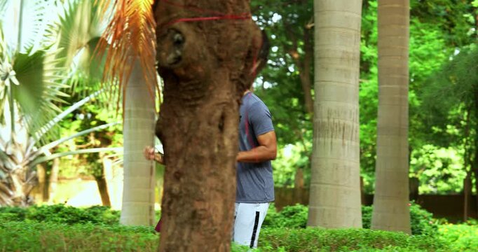 Indian young couple jogging in park together enjoying healthy morning routine and fitness oriented start of the day, spending quality time outdoors breathing fresh air surrounded in sunshine