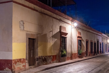 A building with a yellow and red facade. The building is old and has a lot of windows. Historic center of Queretaro, colonial architecture, decorations for the celebration of Mexico's Independence Day