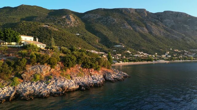 Scenic coastal view transitions from rocky shoreline to lush hills, capturing the serene beauty of nature and the tranquil atmosphere of a beachside retreat