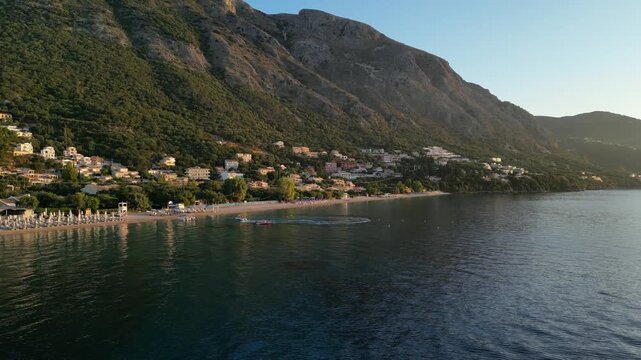 Barbati Beach. Scenic coastal view transitions from serene beach to vibrant water activities, showcasing the dynamic beauty of a tranquil seaside environment at sunset