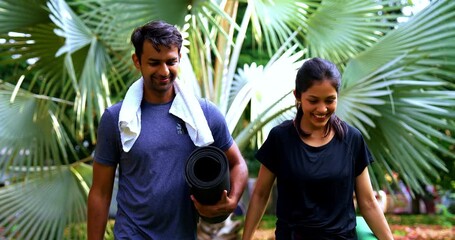 Indian beautiful young couple high five post yoga session with mat outdoors in park celebrating successful morning practice, enjoying wellness, fitness, and fresh air together surrounded by greenery - Powered by Adobe