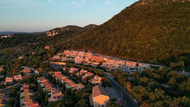 Aerial view captures the serene landscape of a coastal resort nestled among lush hills, showcasing vibrant architecture and natural beauty in a seamless motion sequence