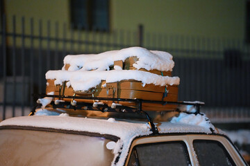 A roof rack on a car with suitcases covered in snow on it.