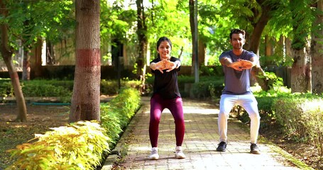 Indian beautiful young couple doing squats together in park outdoor on sunny day as part of their daily fitness routine, focusing on strength, health, motivation, and active healthy lifestyle goals - Powered by Adobe