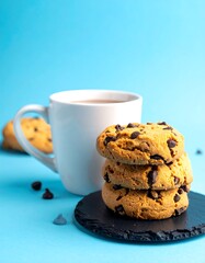 Stacked chocolate chip cookies next to a white mug of hot cocoa
