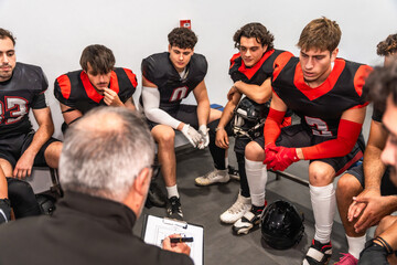 Coach explaining strategy to american football team in locker room