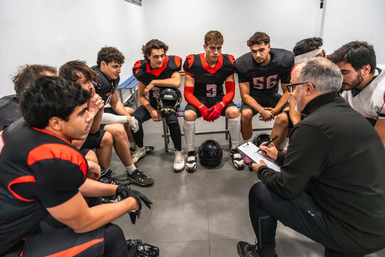 American football coach reviewing strategy with players in locker room