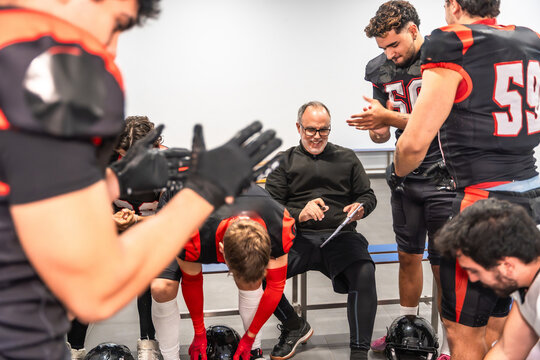 American football coach reviewing strategy with team in locker room