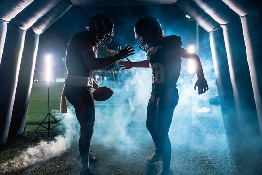 American football players emerging from tunnel for night game