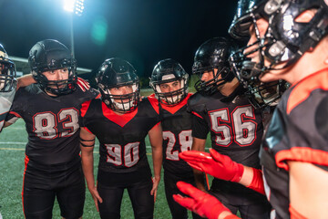 American football team huddling during a night game plan
