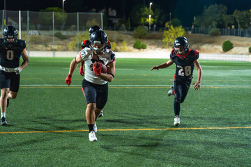 American football players running offense during night game