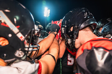 American football players huddling, showing teamwork and motivation