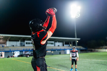 American football player catching ball during night game