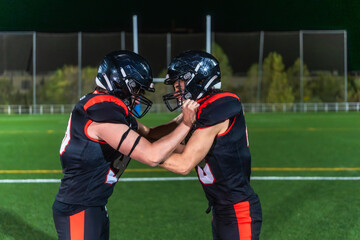 American football players confronting on stadium field at night