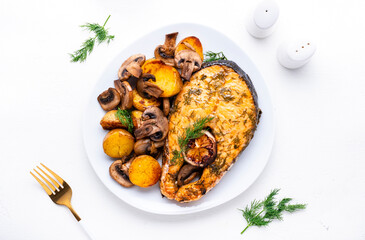 Delicious festive dinner with baked salmon, grilled potatoes and mushrooms with creamy pesto sauce, white table background, top view