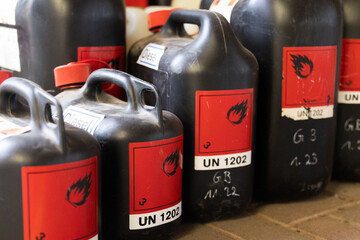 Mehrere schwarze Chemikalienkanister mit Gefahrstoffkennzeichnung stehen geordnet in einer industriellen Umgebung. Das Motiv steht f&uuml;r Gefahrgut, sichere Lagerung und professionelle Handhabung von Che