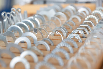 Reihen von metallischen Bauteilen sind gleichm&auml;&szlig;ig in einer Werkstatt oder Produktionsumgebung angeordnet. Das Motiv steht f&uuml;r industrielle Fertigung, Ordnung und pr&auml;zise Serienproduktion.