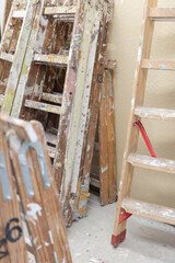 Gebrauchte Leitern stehen in einem Werkraum mit Farbspritzern und Gebrauchsspuren. Das Motiv steht f&uuml;r Handwerk, Renovierung und laufende Bau- oder Malerarbeiten.