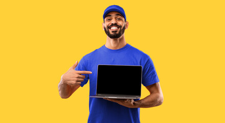 Arab Delivery Guy Showing Laptop Empty Screen Advertising Courier Service Or Website Smiling To Camera Standing In Studio Over Yellow Background. Man In Red Uniform Posing With Computer. Mockup