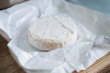 A freshly unwrapped round Camembert cheese with white mold, ready for gourmet dining and food photography