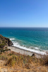Turquoise waves of the sea near Herradura, Spain, gently rolling toward the shore under bright sunlight.
