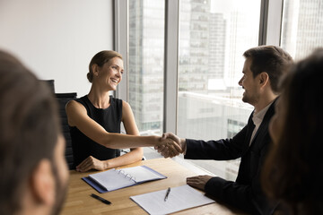 Two business partners man woman handshake reach agreement on negotiation