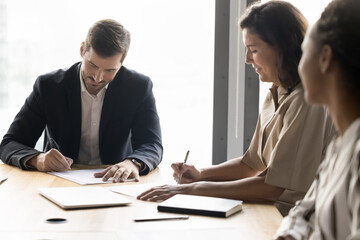 Young businessman mature woman client put signatures on document copies