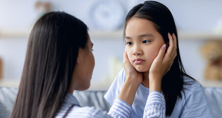 Childhood problems concept. Young mother comforting her sad offended daughter after quarrel at...